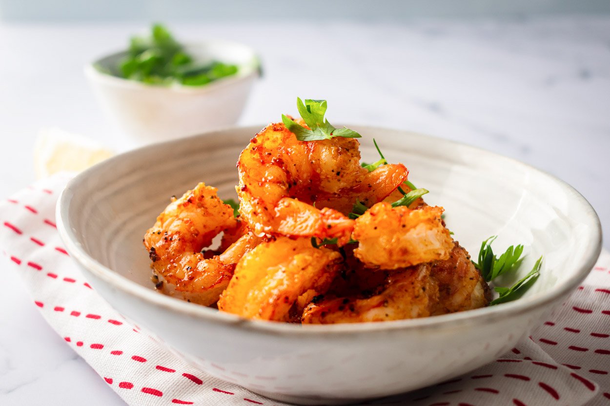 Air fryer shrimp in a bowl with fresh cilantro.