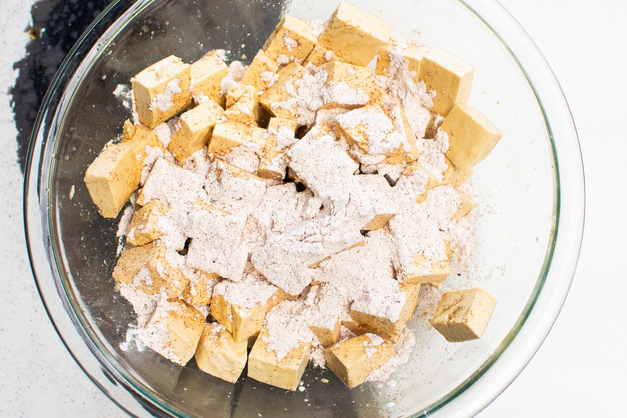 Cornstarch mixture on marinated tofu in glass bowl.