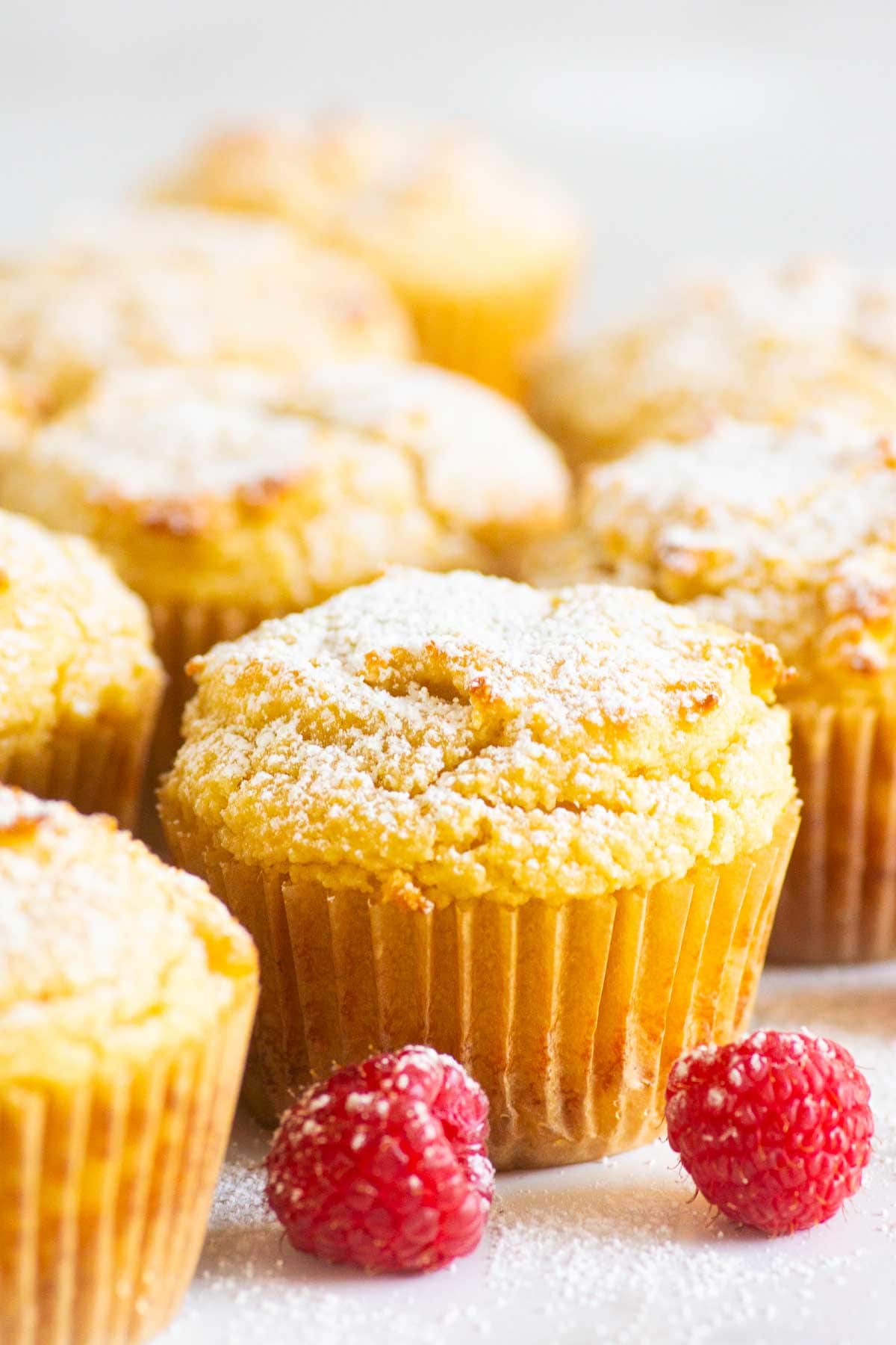 Almond flour yogurt muffins in paper liners with fresh raspberries.