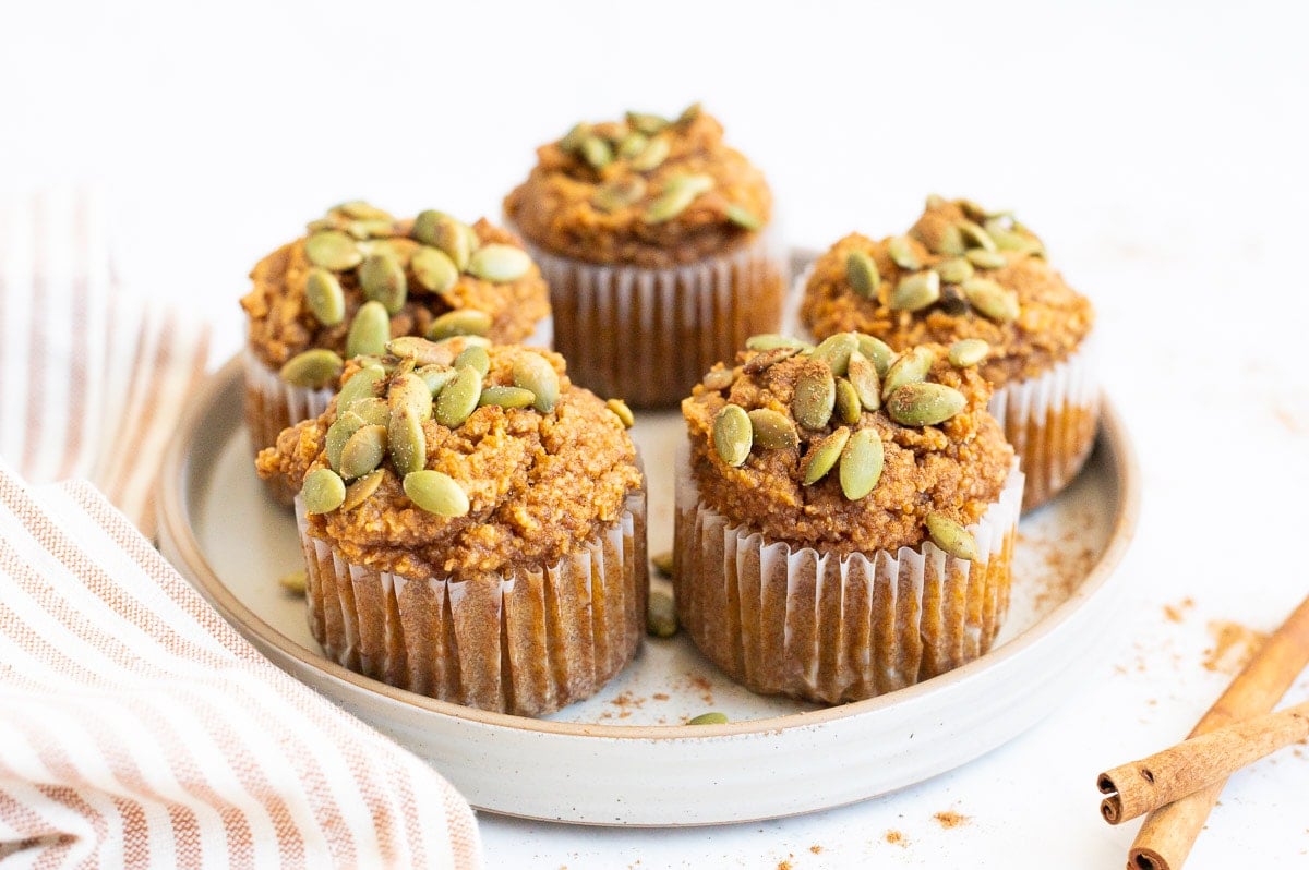 Almond flour pumpkin muffins on a plate with cinnamon sticks. 
