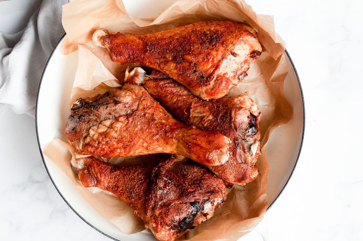 Four baked turkey drumsticks on a platter.