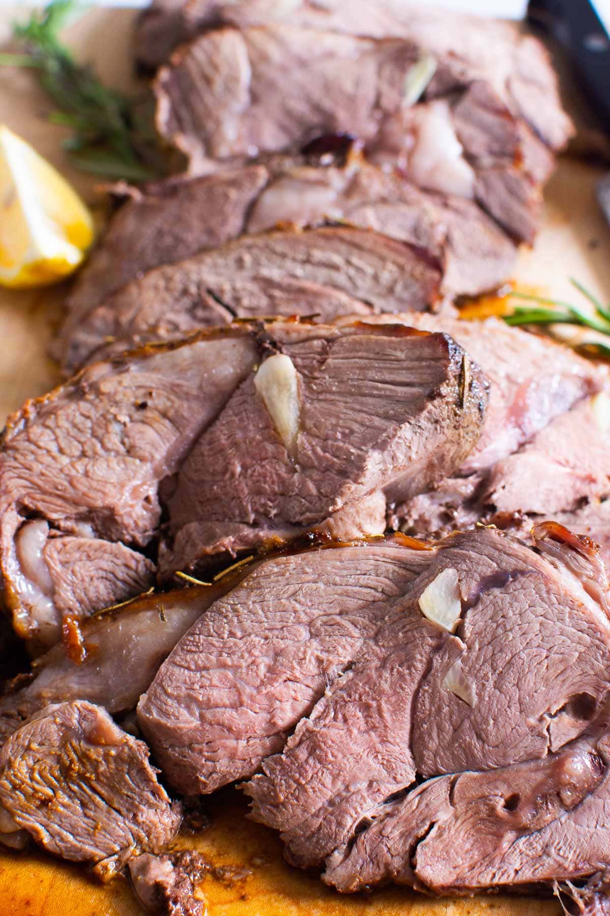 Sliced boneless leg of lamb roast on a cutting board.