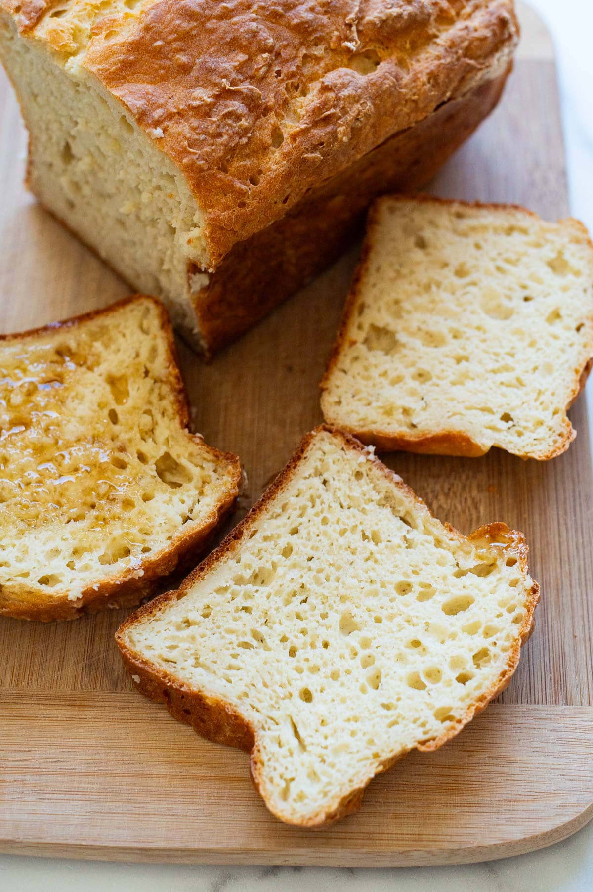 Sliced bread drizzled with honey on a cutting board.