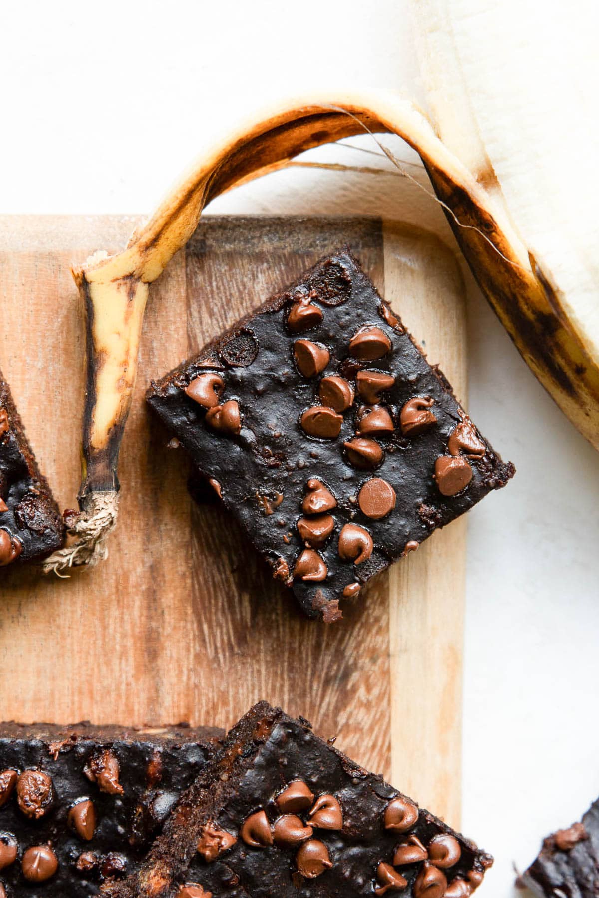 Banana brownie on a cutting board with a banana peel.