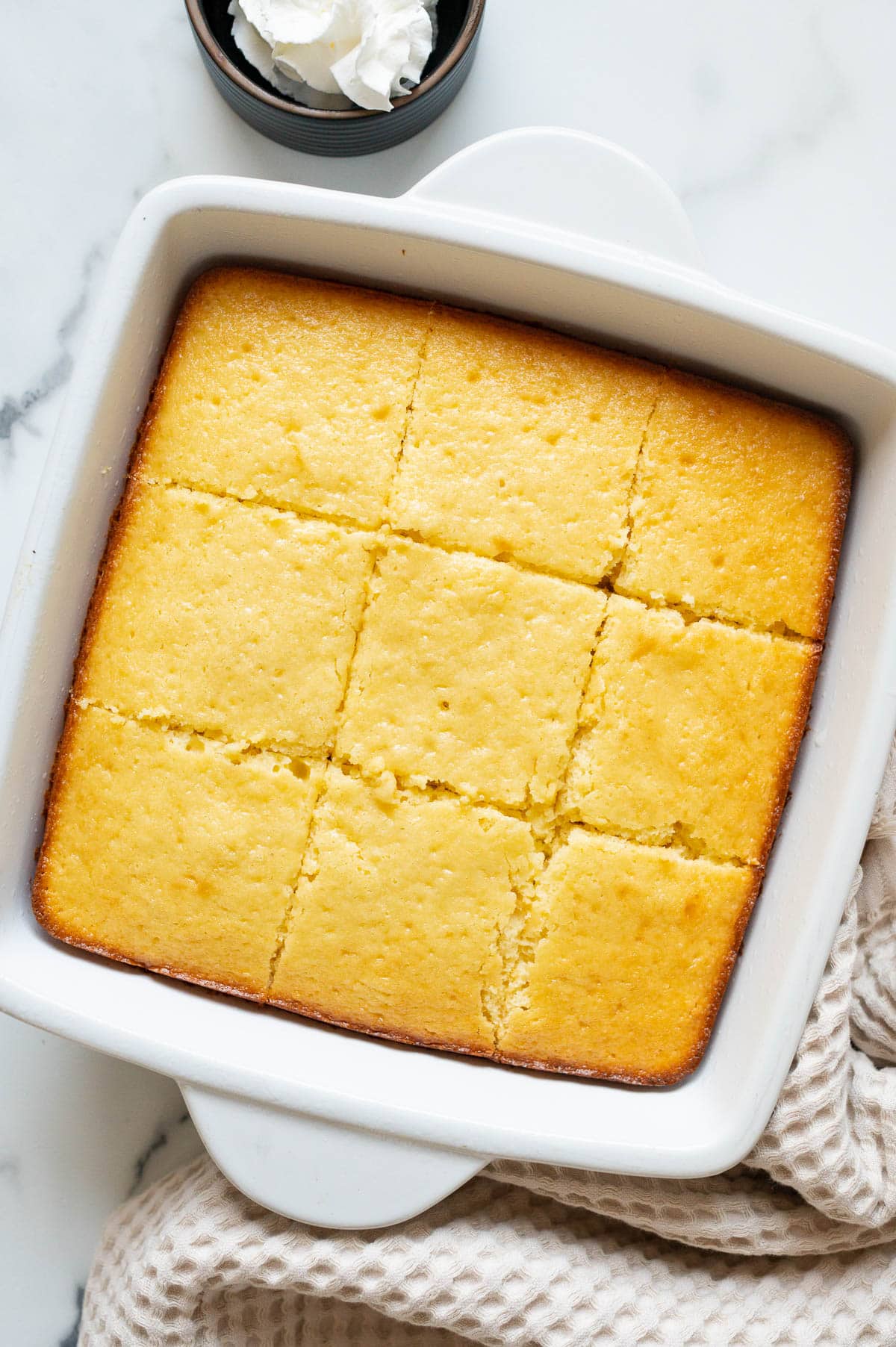 Sliced Greek yogurt cake in a square baking dish.
