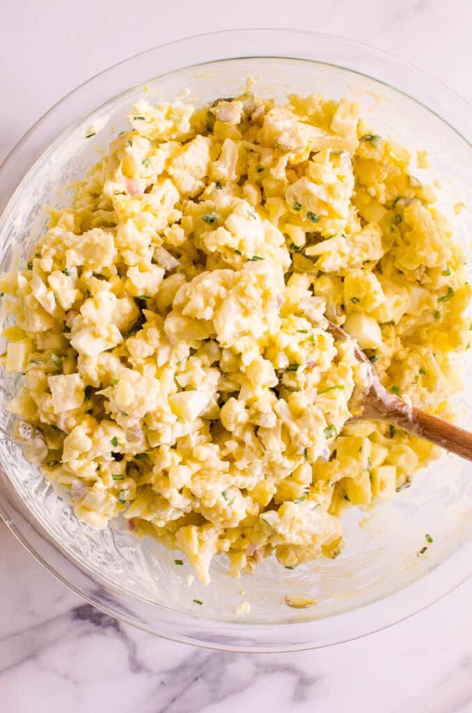 Cauliflower potato salad in a bowl with spoon.