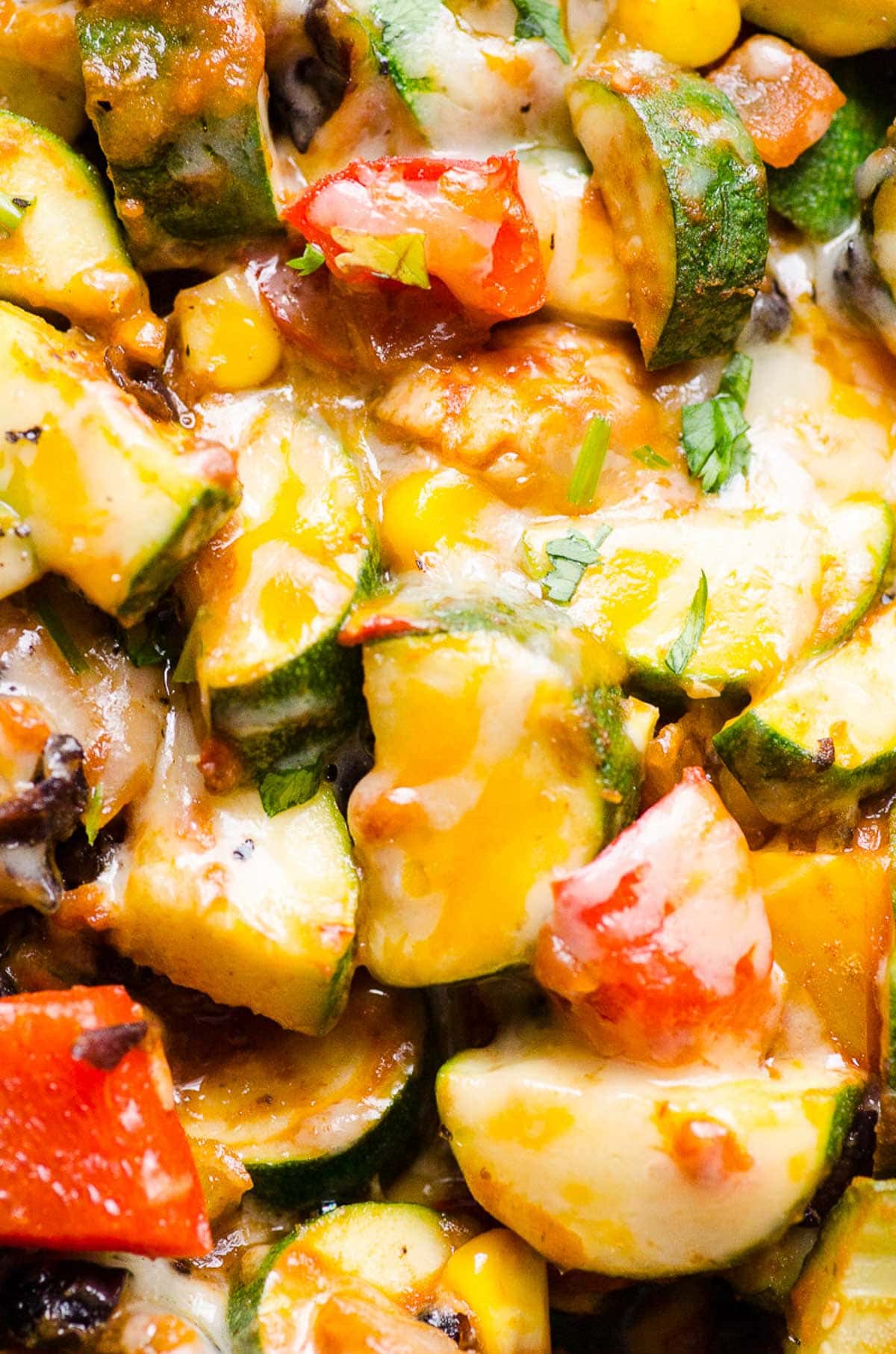 Closeup of melted cheese on chicken and zucchini skillet.