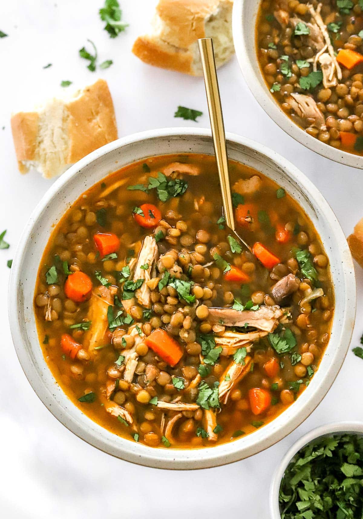Chicken lentil soup with carrots and parsley in a bowl with spoon.