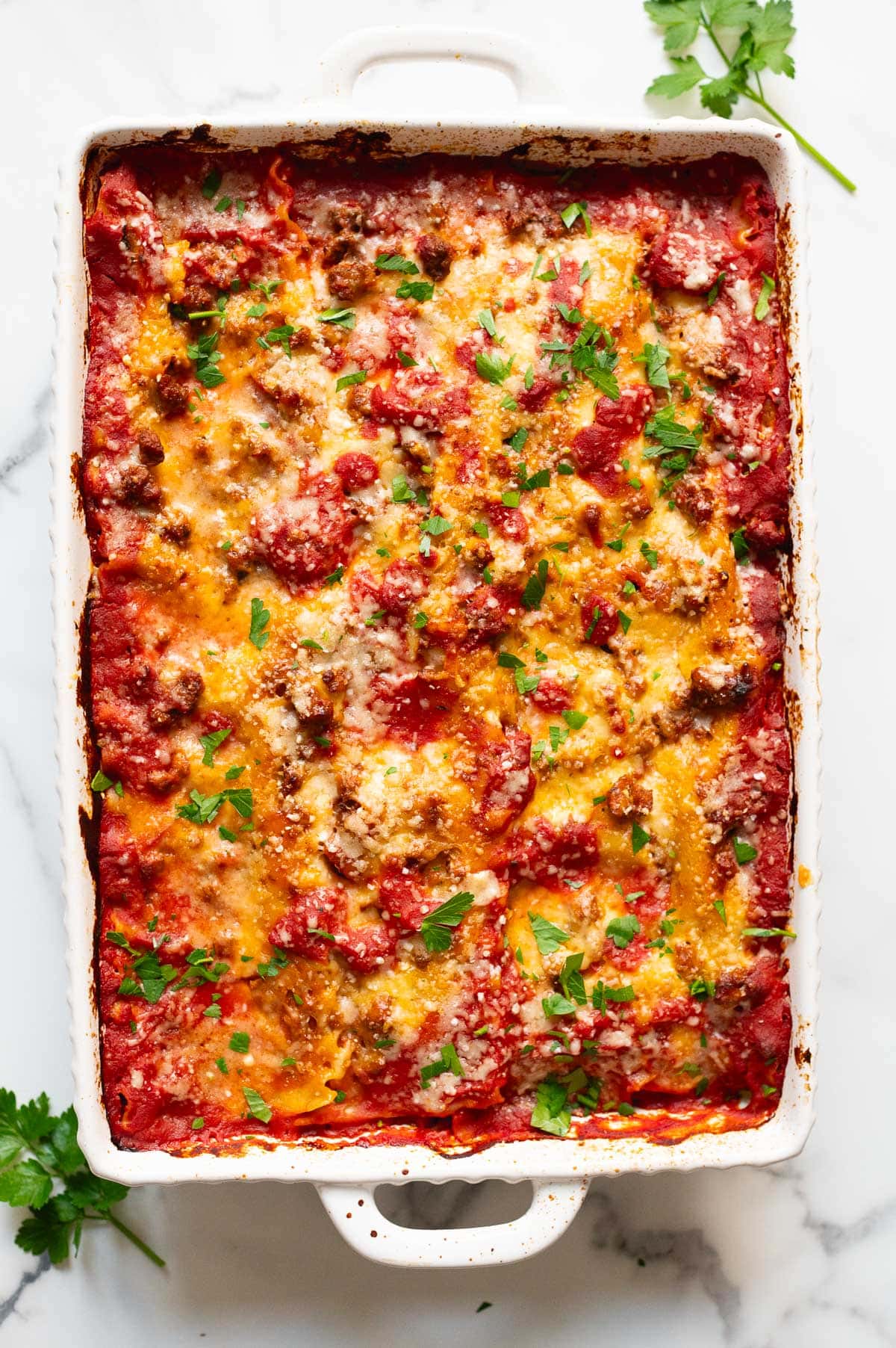 Baked lasagna with cottage cheese garnished with parsley in a baking dish.