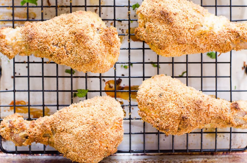 Fried chicken drumsticks on a cooling rack.