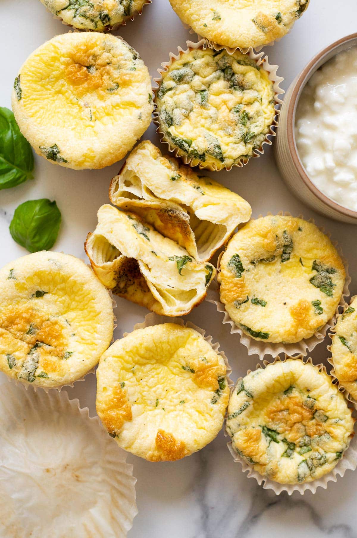 One egg bite cut in half and showing texture and more egg bites with cottage cheese around it.