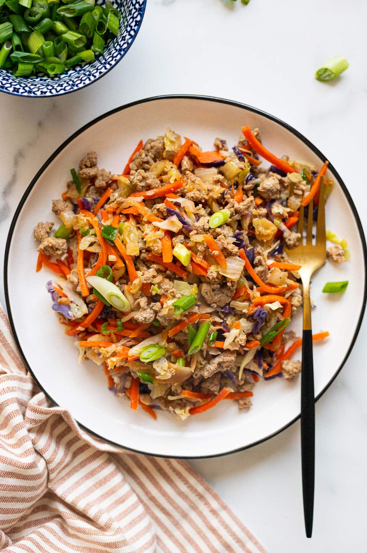 Egg roll in a bowl with ground turkey served on white plate with a fork.