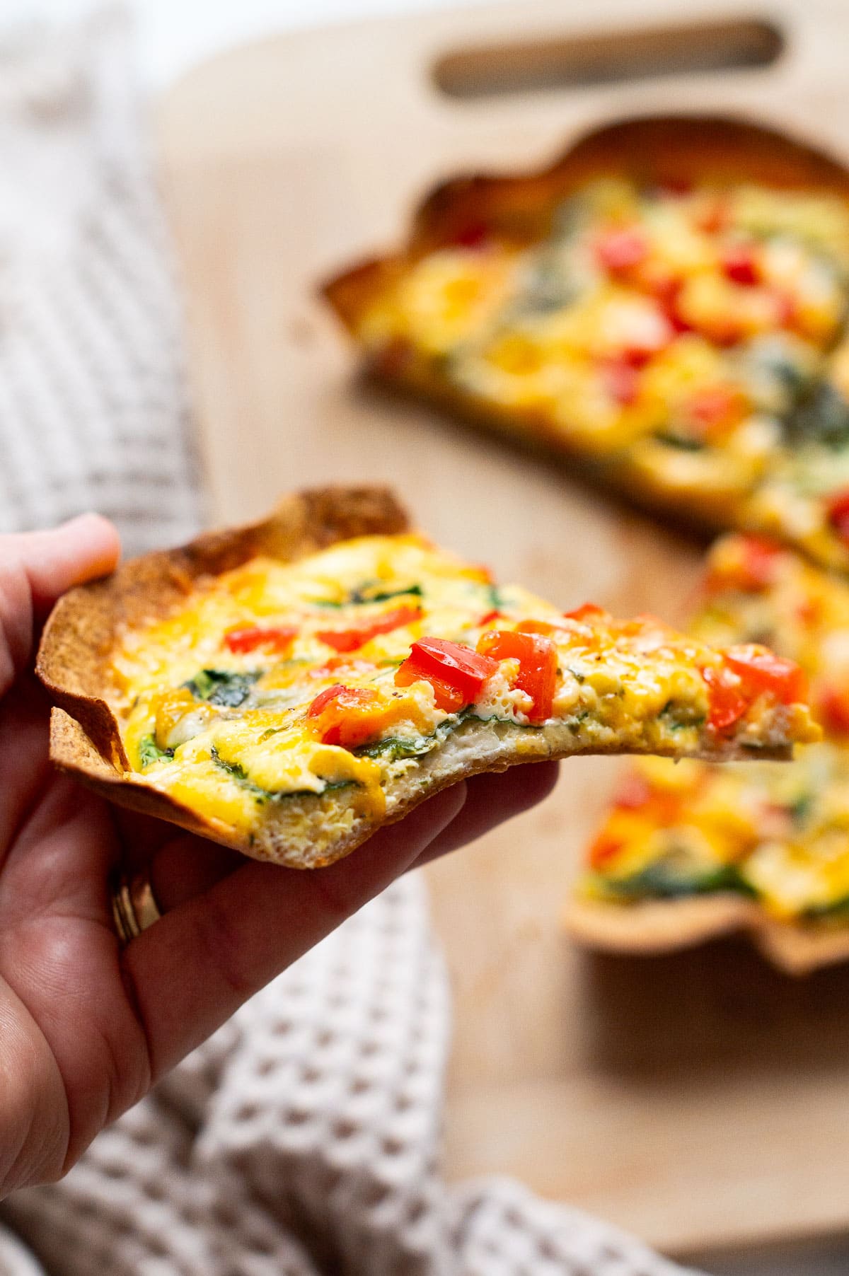 Person holding a slice of baked egg tortilla showing texture.