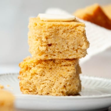Two slices of almond flour cornbread with butter on a plate.
