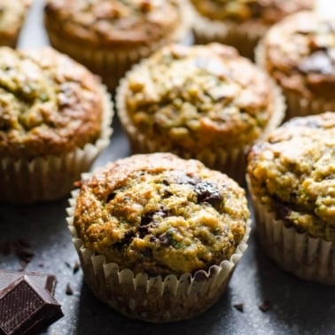 Healthy banana zucchini muffins with dark chocolate on counter.