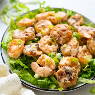 Bang Bang Shrimp served on a bed of lettuce on a plate.