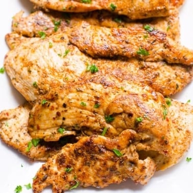 Cajun chicken garnished with parsley and served on white plate.
