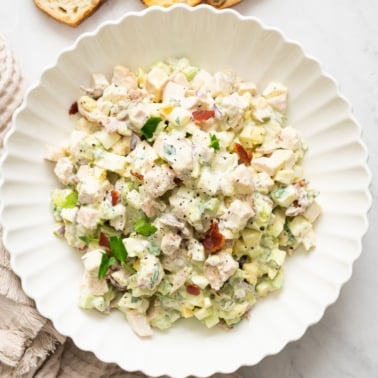 Chicken egg salad with bacon on white plate.