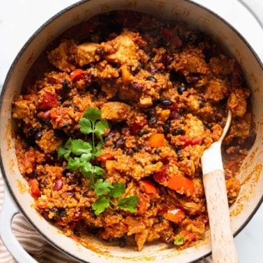Chicken quinoa chili garnished with cilantro in a pot with a spoon.