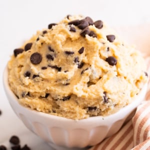 Cottage cheese cookie dough in a bowl. Linen towel and chocolate chips on a counter.