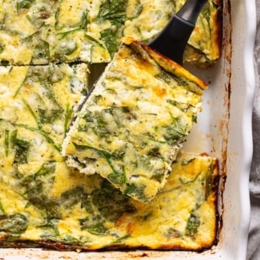 Slice of cottage cheese egg bake with spinach on a spatula.