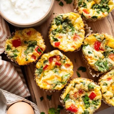 Cottage cheese egg muffins on a wooden board with a bowl of cottage cheese, egg and napkin.