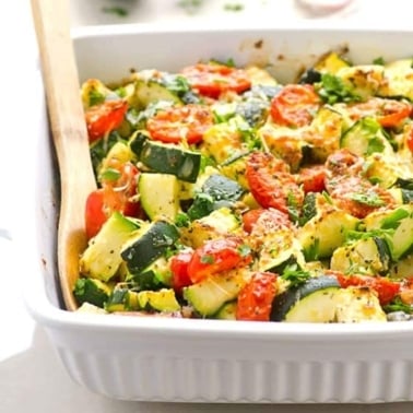 Zucchini tomato bake in white casserole dish.