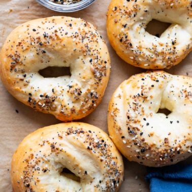 4 Greek yogurt Bagels on a baking sheet. A bowl with everything bagel seasoning and blue napkin.