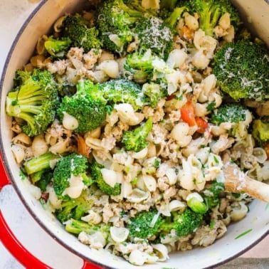Ground turkey and broccoli pasta in large red pot with parmesan.