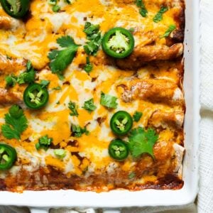 Healthy chicken enchiladas with melted cheese, cilantro and jalapeno on top.