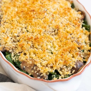 Healthy green bean casserole with parmesan breadcrumb topping in white dish.