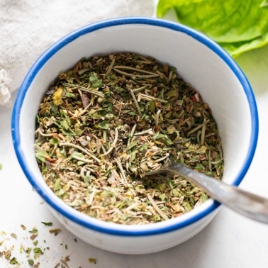 Italian seasoning in white bowl with a spoon.