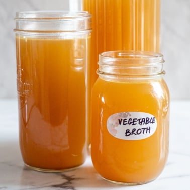 Homemade vegetable broth in three glass jars and one of them labeled.