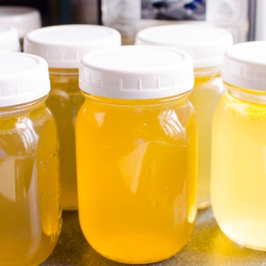 Instant Pot beef bone broth in glass jars with lids and pressure cooker in the background.