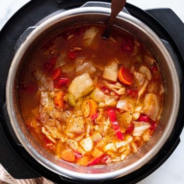 Cabbage soup in Instant Pot with a ladle.
