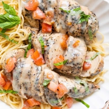 Sliced Italian chicken breasts served over spaghetti.