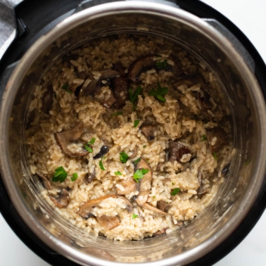 Instant Pot mushroom risotto garnished with parsley in a pressure cooker.