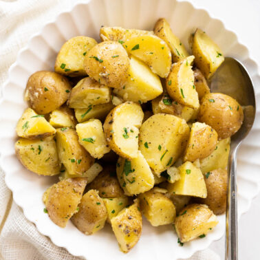 Instant Pot potatoes with fresh herbs served in a bowl with a spoon.