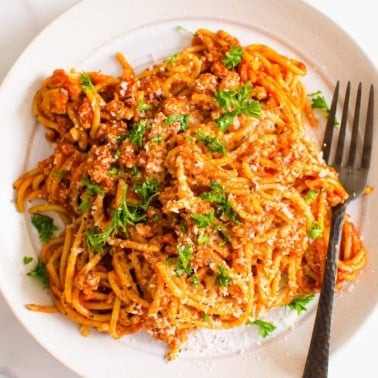 Instant Pot spaghetti on a plate with garnish and a fork.