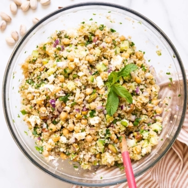 Jennifer Aniston salad with chickpeas, feta cheese or my mint and parsley served in glass bowl with wooden spoon.