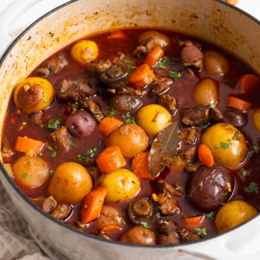 Lamb stew with carrots and potatoes in white pot.