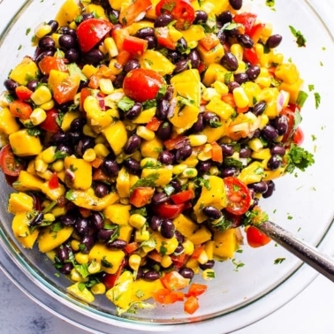 Mango black bean salad in glass bowl with a spoon.