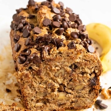 Sliced oat flour banana bread with walnuts and chocolate chips on parchment paper.