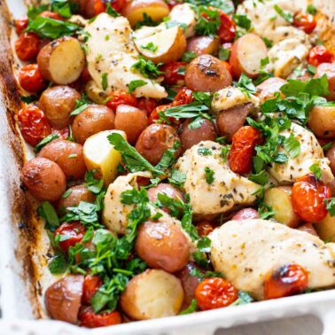 One pan chicken and potatoes in baking dish with fresh parsely.