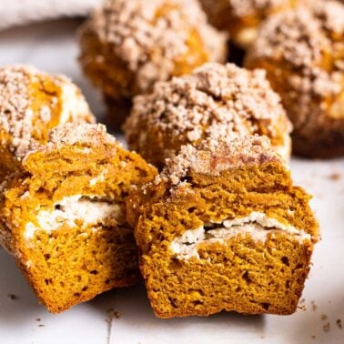 Pumpkin cream cheese muffin sliced in half showing texture and filling inside.