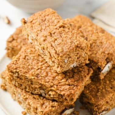 Pumpkin protein bars stacked on white plate.