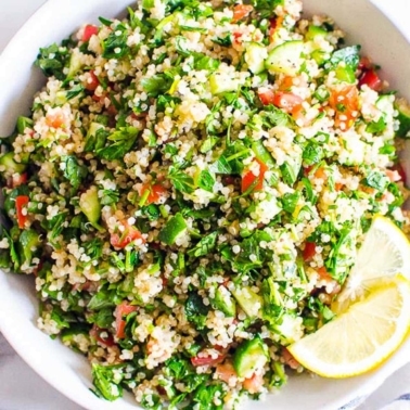 Quinoa tabbouleh salad on a white deep plate with lemon slices.