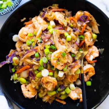 Shrimp egg roll in a bowl served in black bowl with a fork.