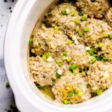 Porcupine meatballs in slow cooker garnished with green onion.