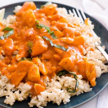 Thai chicken curry served on a bed of rice and garnished with basil on a plate.